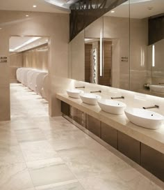 a row of sinks in a bathroom with mirrors on the wall and lights above them