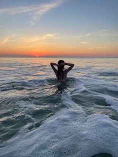 a person sitting in the water at sunset