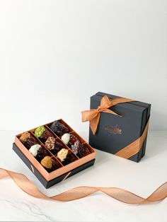 an open box of chocolates next to a ribbon