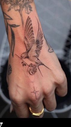 a hand with a bird and flower tattoo on it