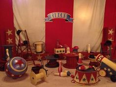 a room filled with lots of different types of toys and decorations on the floor in front of a red wall