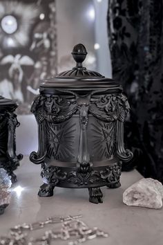 an ornate black urn sitting on top of a table next to a crystal ball