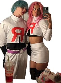 two people dressed in costumes standing next to each other holding cell phones and drinking beverages