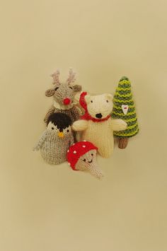 several knitted animals are hanging on a white wall in the shape of christmas trees