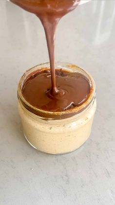 chocolate sauce being poured into a glass jar