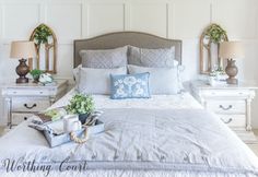 a bed with white sheets and pillows in a bedroom next to two lamps on either side of the bed