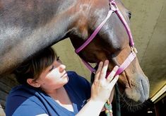 a woman standing next to a brown horse