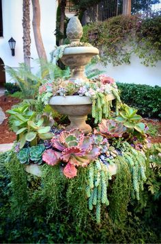 an outdoor fountain surrounded by plants and trees