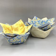 three paper bowls with yellow and blue designs on the inside one is folded in half