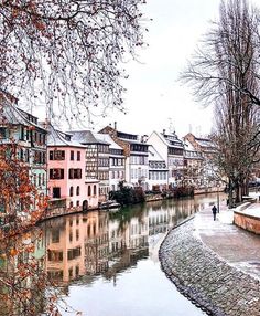 a river running through a small town next to tall buildings on the side of it