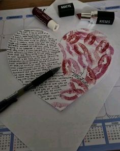 a heart shaped piece of paper with lipstick on it next to some writing and markers