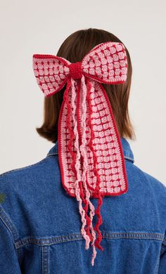 a woman wearing a denim jacket with a pink crochet bow on her head