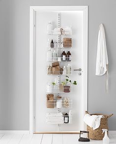 a white door with baskets and towels hanging on the wall next to an open closet