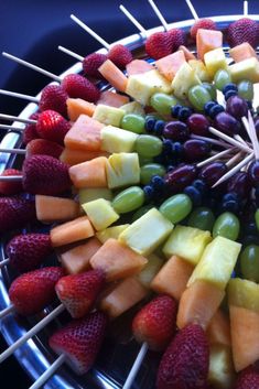 an assortment of fruits arranged on skewers in a circular arrangement with strawberries, grapes, and melon