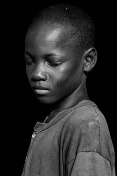 a black and white photo of a young boy with his eyes closed, looking to the side