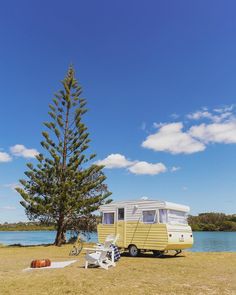 an rv parked next to a tree near the water