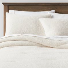 an unmade bed with white linens and pillows