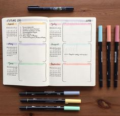 an open planner with pens and markers on a wooden table next to two notebooks