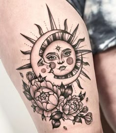 a sun and moon tattoo on the right thigh, with flowers in front of it