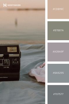 a polaroid camera sitting on top of a bed next to a pillow and blanket