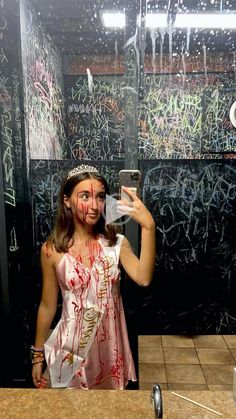 a woman with makeup on taking a selfie in front of a mirror covered in graffiti