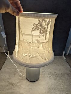 a person is holding up a lamp that has been made to look like a beach scene