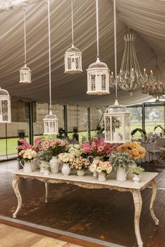 a table topped with lots of vases filled with flowers next to a chandelier