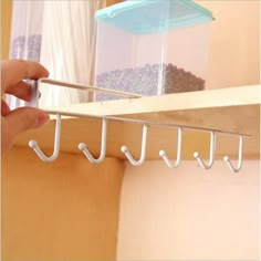 a person is holding two hooks on a shelf