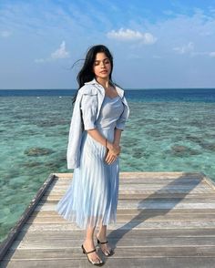 a woman standing on a dock in front of the ocean