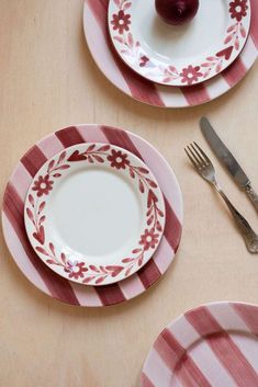 two plates with red and white designs on them, one has an apple in the middle