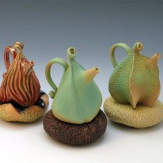 three ceramic teapots sitting on top of each other in different shapes and sizes