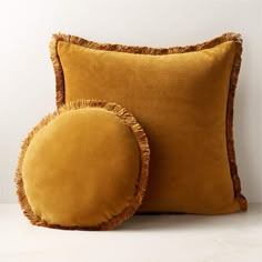 two yellow pillows with ruffled edges on a white surface, next to each other