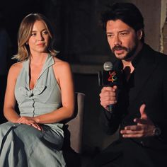 a man and woman sitting next to each other holding microphones in front of them