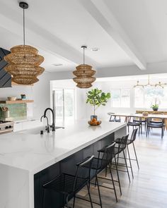 a large kitchen with an island and bar stools next to it, along with two hanging lights