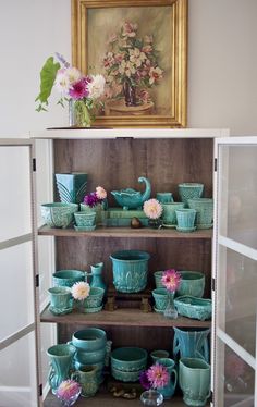 a cabinet filled with dishes and vases on top of it