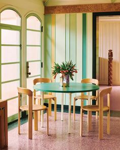 a dining table with four chairs and a potted plant on the table in front of it