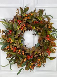 a wreath with leaves and berries hanging on the front door to decorate it for fall