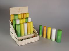 an assortment of colorful candles in a wooden box with four smaller ones next to them