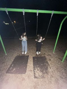 two girls playing on swings in the dark