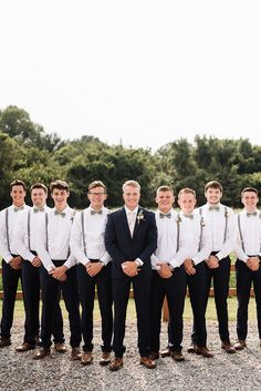 a group of young men standing next to each other in front of a lush green forest