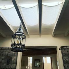 a light fixture hanging from the ceiling in a room with two windows and a door