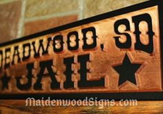 a wooden sign that says deadwood, sd jail on it's side against a brick wall