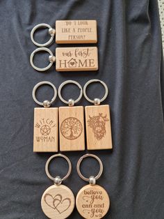 six wooden key chains with engraved words and symbols on them, arranged in a row