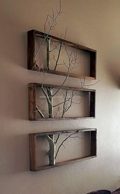 two wooden frames with trees on them are hanging on the wall above a bed in a bedroom