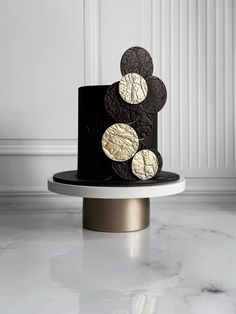 a black and white cake with gold circles on top