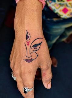 a woman's hand with a tattoo on her left wrist and an evil face