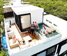 two men are standing on the roof of a house with an inflatable pool