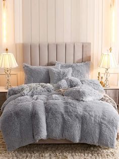 the bed is made up with fluffy blankets and pillows on top of it, along with two lamps