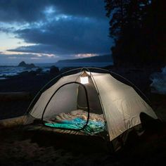 a tent is set up on the beach at night, with its lights turned on