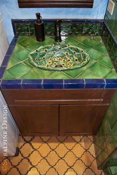 a bathroom sink with green and blue tiles